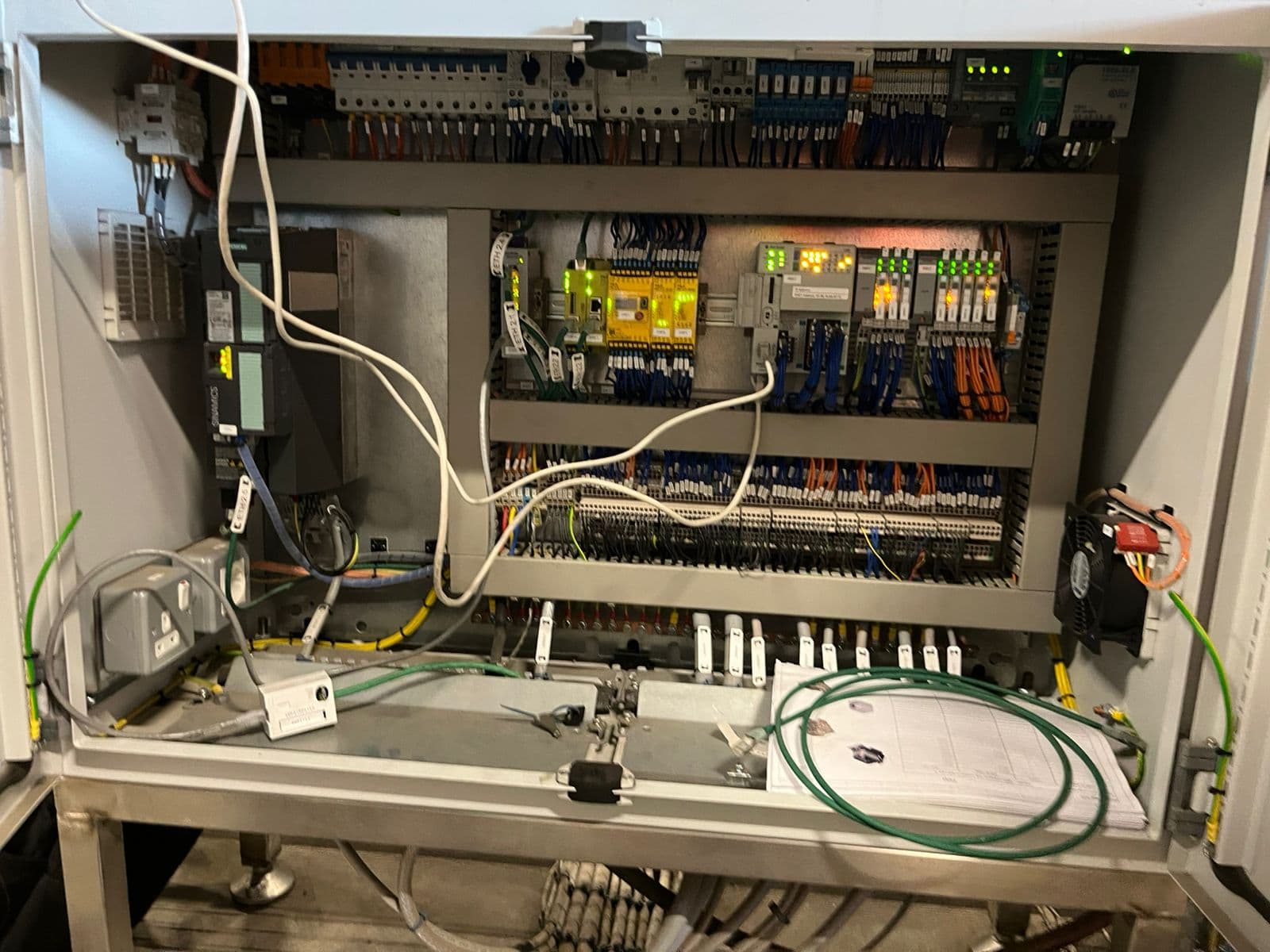 Open control panel showing a yellow PILZ safety relay wired alongside a Siemens SINAMICS drive and distributed safety I/O.