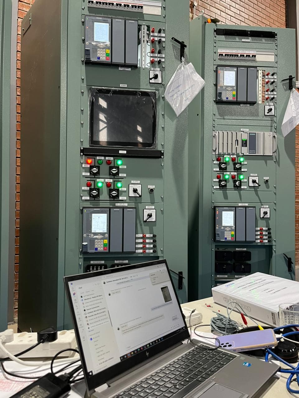Siemens SIMATIC rack PCs and protection relays under factory acceptance test, with a laptop running the simulation.