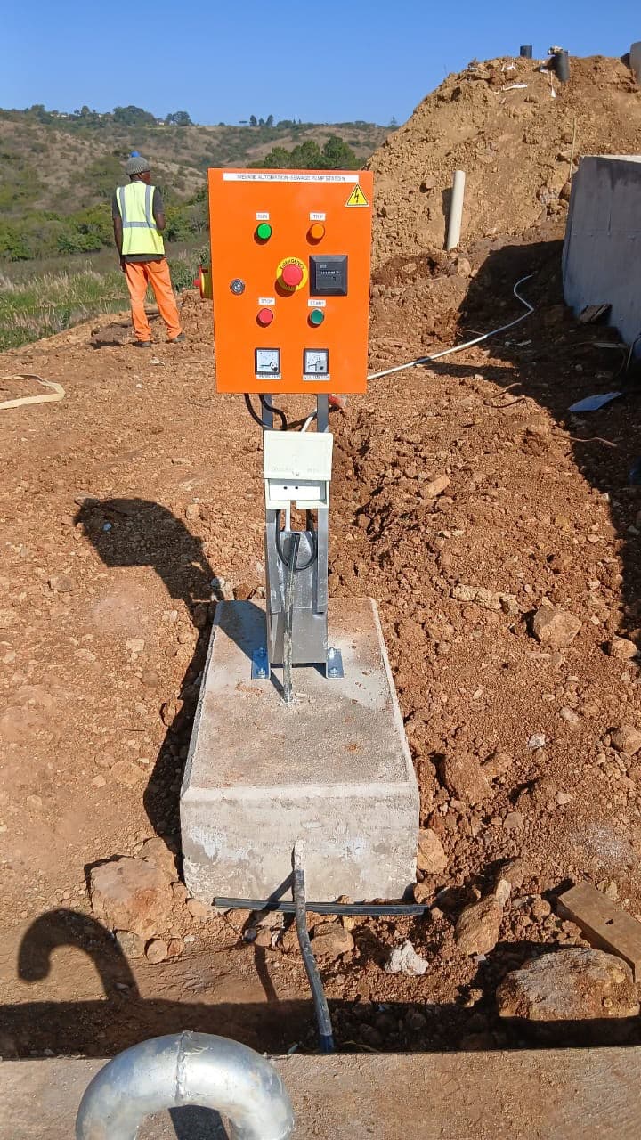 An Ivevane-branded sewage pump station control panel installed on site, start, stop and emergency stop controls visible, with a technician working behind it.
