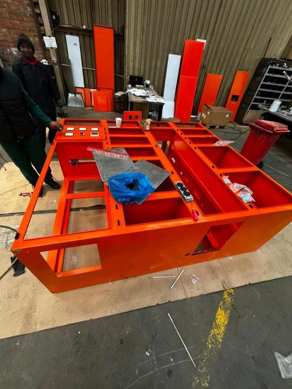 Orange powder coated frame with door panels being prepared for fitting