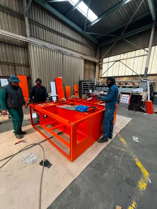 Workshop team beside a powder coated orange panel frame